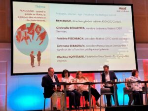 Table ronde lors d’un symposium sur le harcèlement, avec plusieurs intervenants assis sur scène devant un écran indiquant le thème « Prévenir, alerter, agir : la place du dialogue social ».