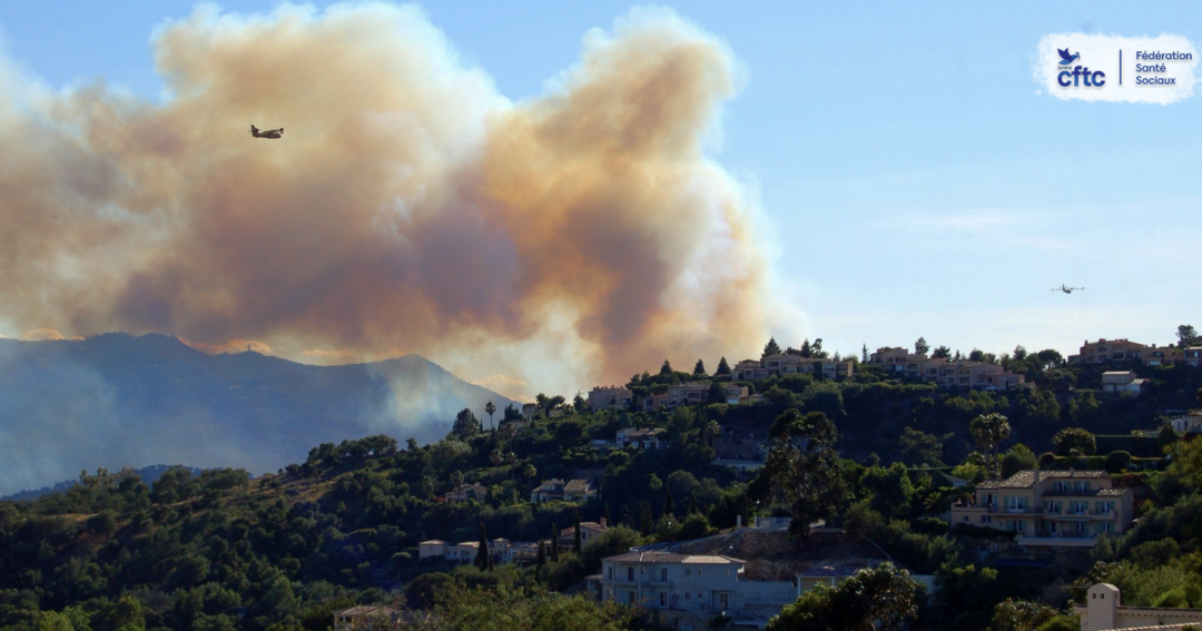 Incendie de forêt menaçant une zone résidentielle, avec des avions de lutte contre le feu